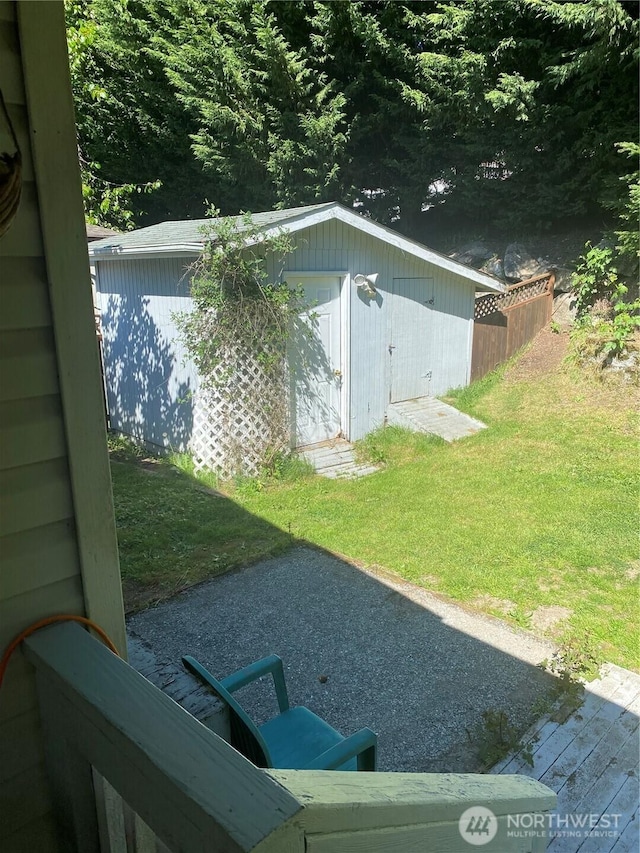 view of grassy yard with a shed, an outbuilding, and a wooden deck