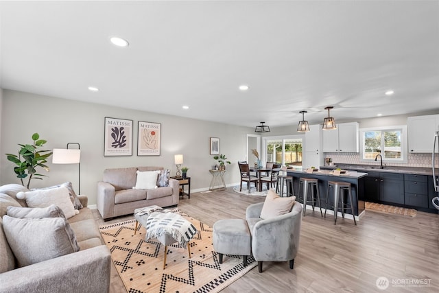 living area featuring baseboards, recessed lighting, and light wood-type flooring
