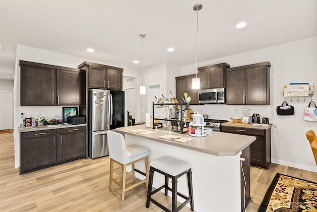 10414 113th Street Ct SW, Lakewood, WA 98498 - kitchen with light countertops, dark brown cabinetry, a kitchen bar, stainless steel appliances, and light wood-style floors