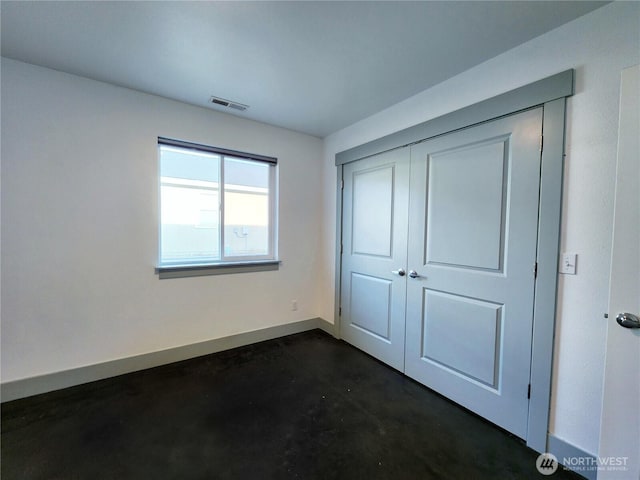 unfurnished bedroom featuring baseboards, visible vents, concrete flooring, and a closet
