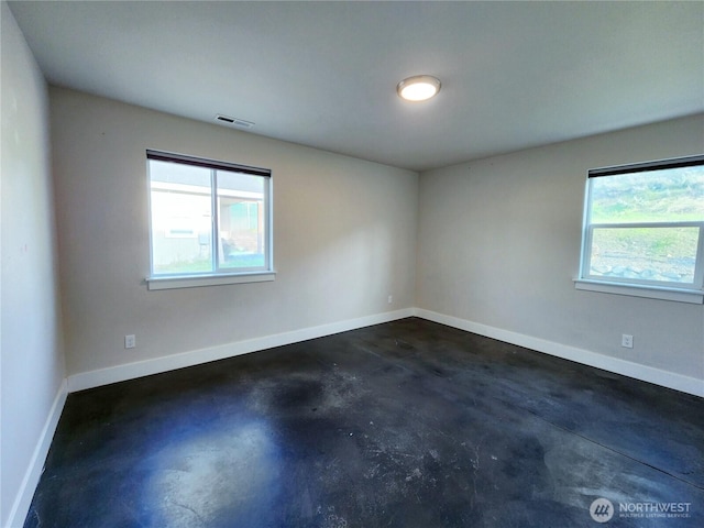 empty room featuring plenty of natural light, visible vents, baseboards, and concrete flooring