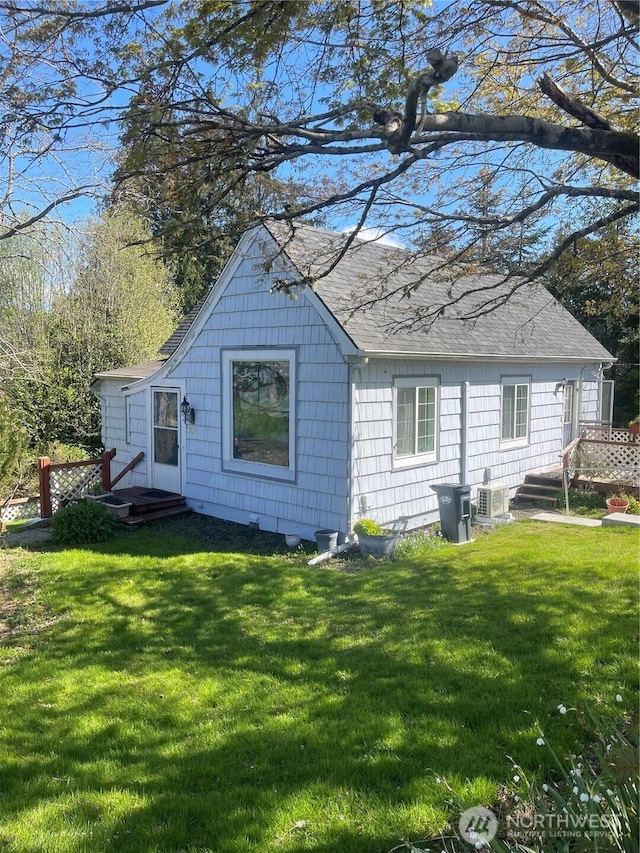 rear view of property featuring a lawn, roof with shingles, and ac unit