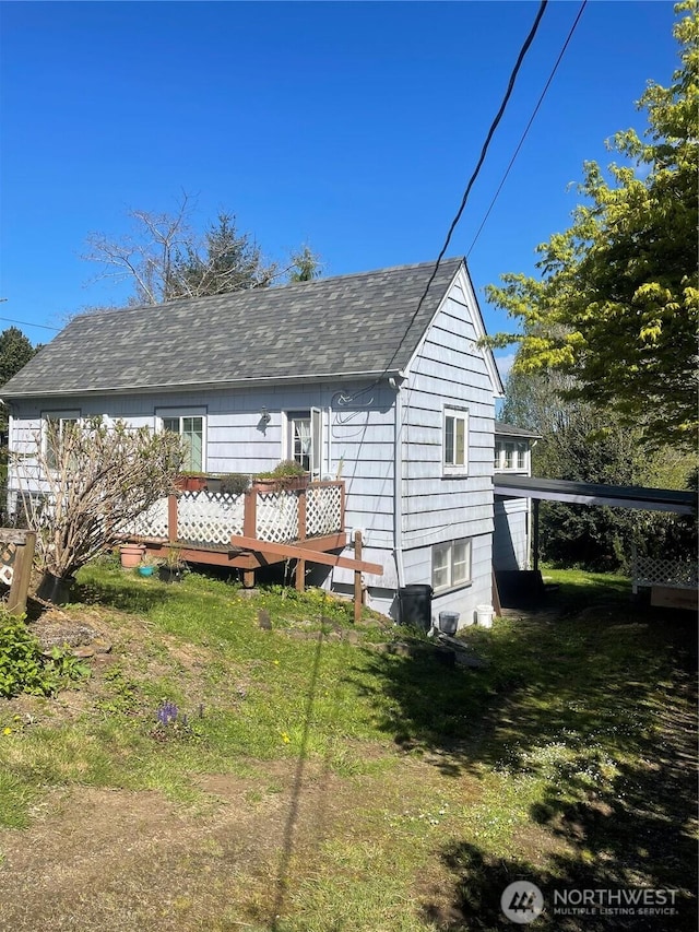 back of house with a shingled roof and a deck
