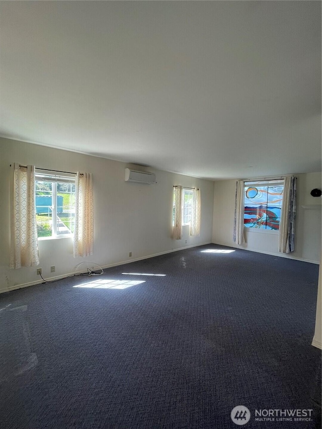 carpeted spare room featuring baseboards, a healthy amount of sunlight, and a wall mounted air conditioner