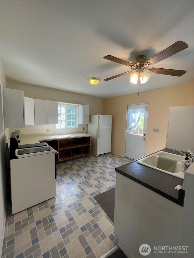 kitchen featuring plenty of natural light, a sink, stove, and freestanding refrigerator