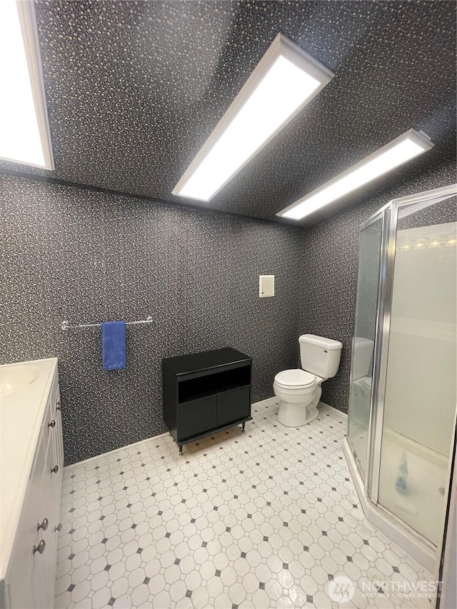 bathroom with a shower stall, toilet, and vanity