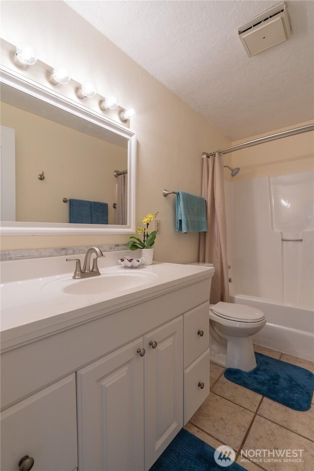 bathroom with a textured ceiling, tile patterned flooring, shower / tub combo, vanity, and toilet