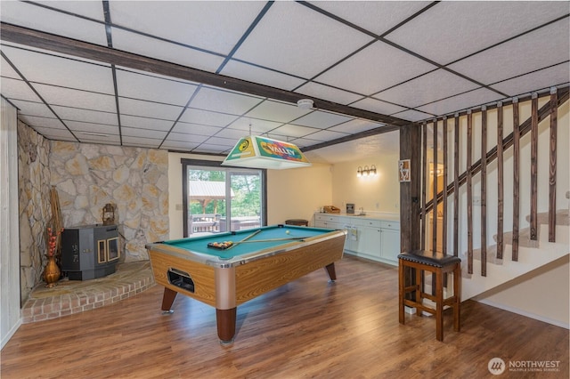 rec room with a wood stove, a paneled ceiling, wood finished floors, and pool table