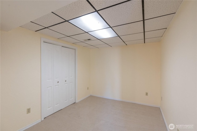 carpeted empty room with baseboards and a drop ceiling