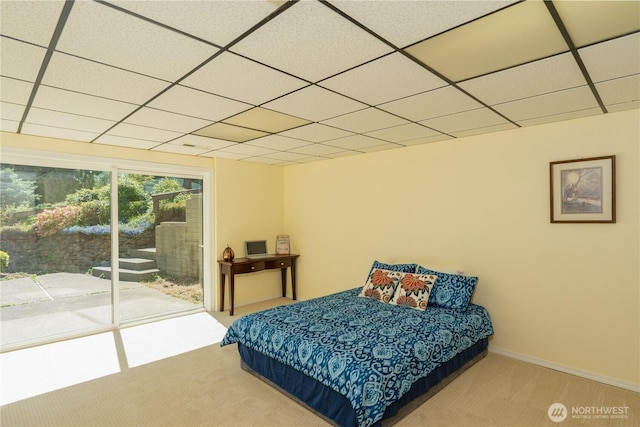bedroom with access to outside, carpet, baseboards, and a paneled ceiling
