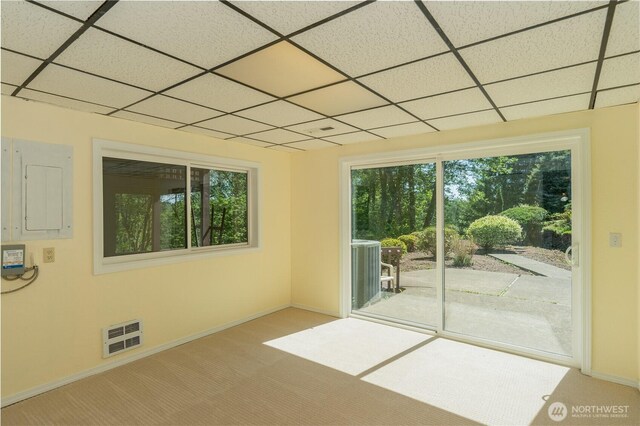 carpeted spare room featuring baseboards, visible vents, and a paneled ceiling