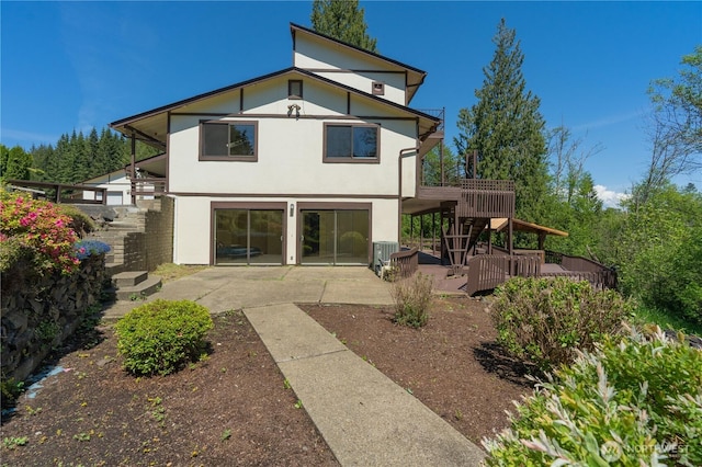 rear view of house with a patio, stucco siding, cooling unit, and a deck