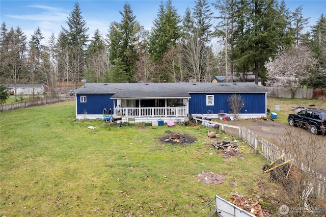 rear view of property featuring fence and a yard