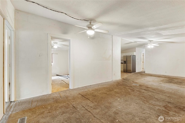 empty room with lofted ceiling, a textured ceiling, visible vents, and a ceiling fan