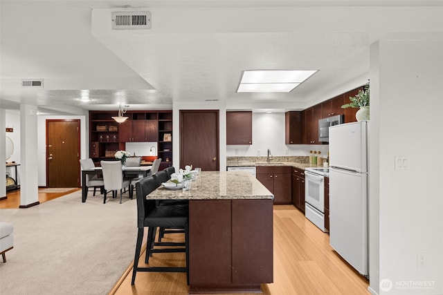 kitchen featuring a sink, visible vents, white appliances, and a kitchen island