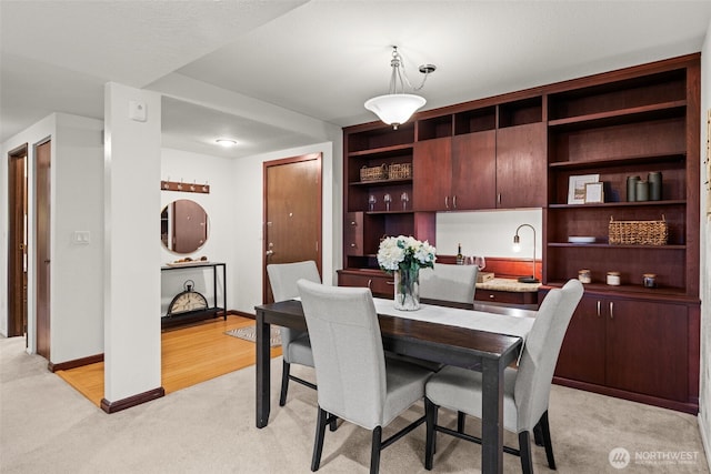 dining space with light colored carpet and baseboards