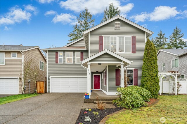 traditional-style house featuring concrete driveway, fence, and an attached garage