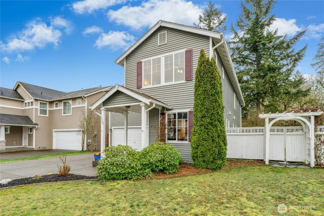 traditional home with driveway, a garage, fence, and a front lawn