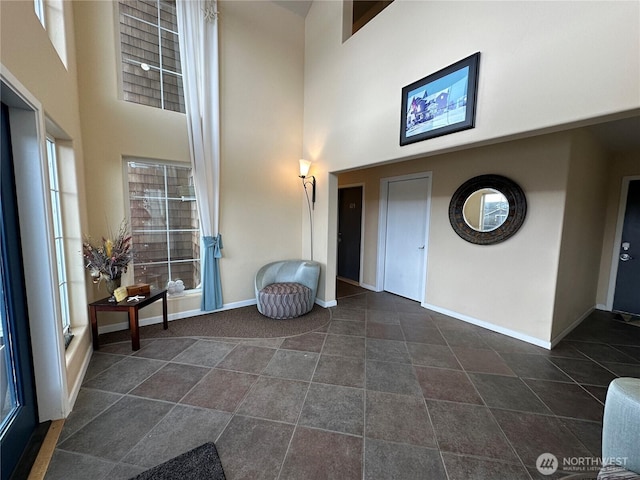 foyer featuring a towering ceiling and baseboards