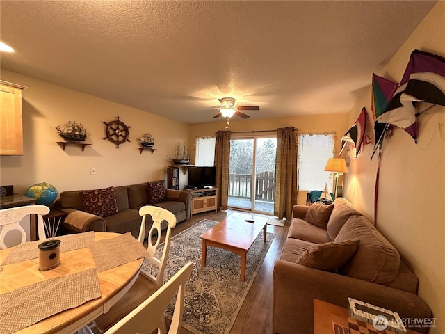 living room featuring a ceiling fan, a textured ceiling, and wood finished floors