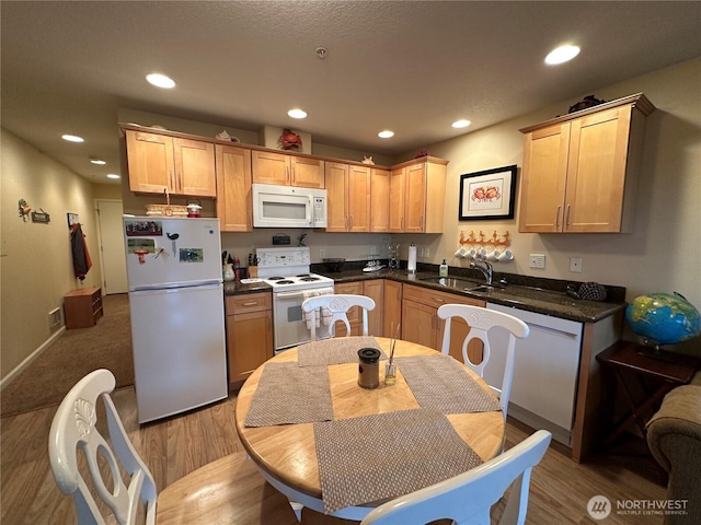 kitchen with white appliances, dark countertops, recessed lighting, a sink, and light wood-style floors