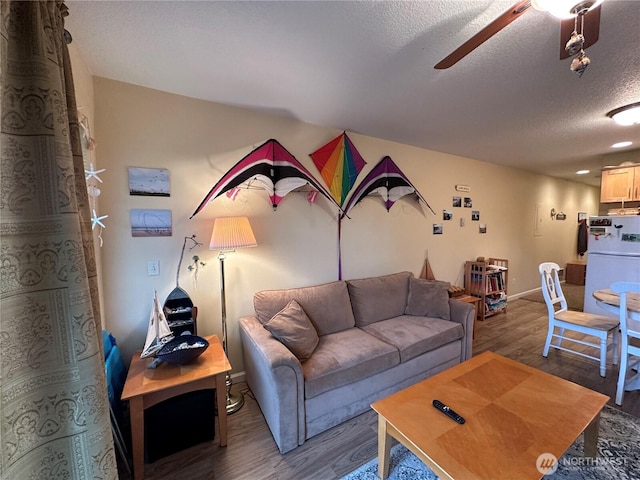 living area featuring a textured ceiling, wood finished floors, and a ceiling fan