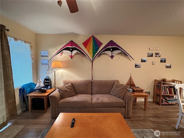living room featuring a textured ceiling, wood finished floors, baseboards, and a ceiling fan