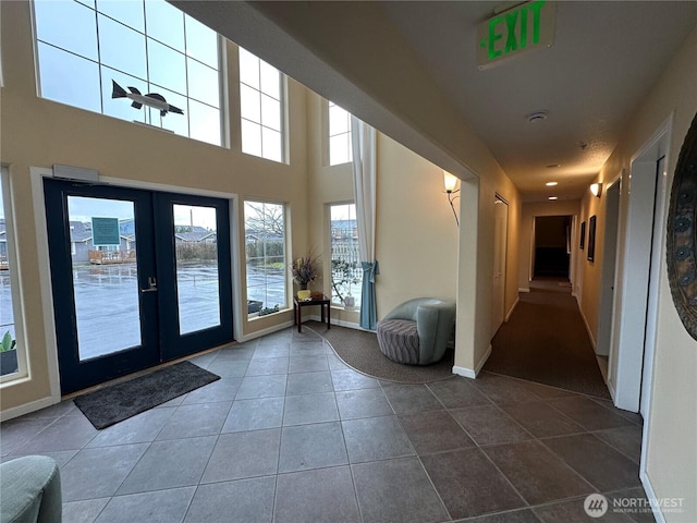 interior space featuring baseboards, a towering ceiling, and french doors