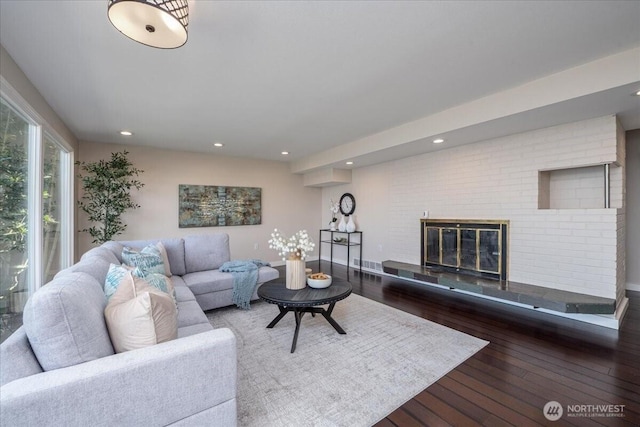 living room with recessed lighting, a glass covered fireplace, and wood finished floors
