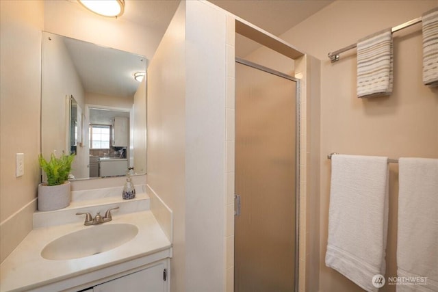 full bath with vanity, a stall shower, and washer / clothes dryer