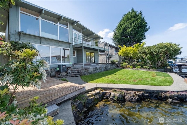 back of property with a lawn, a balcony, and central air condition unit