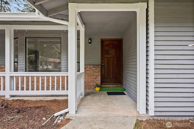 property entrance with covered porch and brick siding