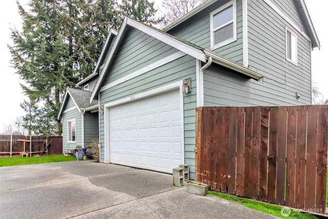 view of property exterior with a garage, driveway, and fence