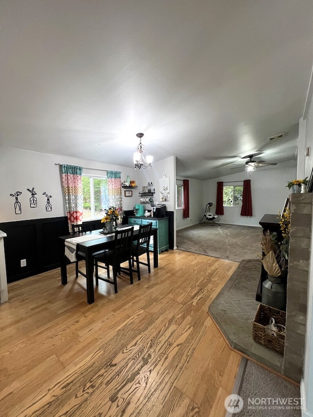 dining space with visible vents, light wood-style floors, and ceiling fan with notable chandelier