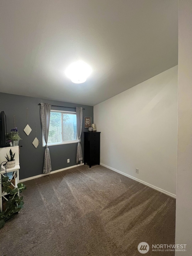 interior space featuring baseboards and dark colored carpet