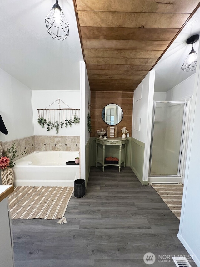 bathroom featuring a shower stall, wood ceiling, a bath, and wood finished floors