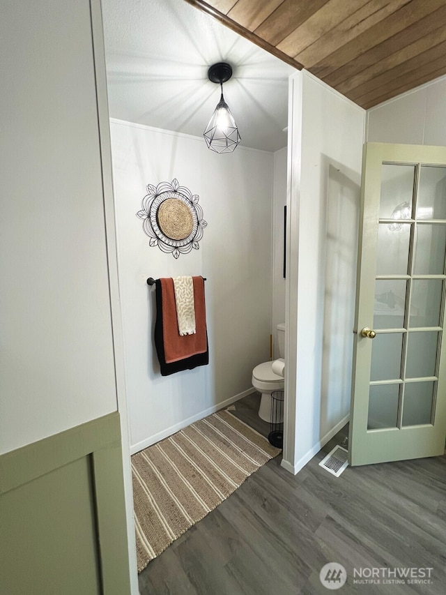 bathroom featuring visible vents, baseboards, toilet, wooden ceiling, and wood finished floors