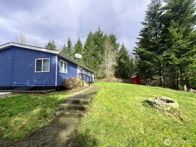 view of yard featuring a storage unit, an outdoor structure, and an outdoor fire pit