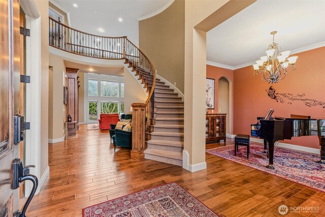 entryway featuring hardwood / wood-style flooring, baseboards, ornamental molding, stairway, and arched walkways