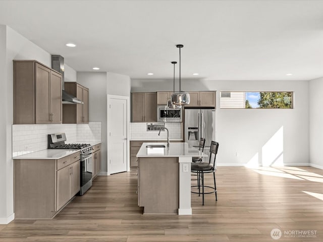 11521 SE 236th St, Kent, WA 98031 - kitchen with stainless steel appliances, a sink, an island with sink, decorative backsplash, and light wood-style floors