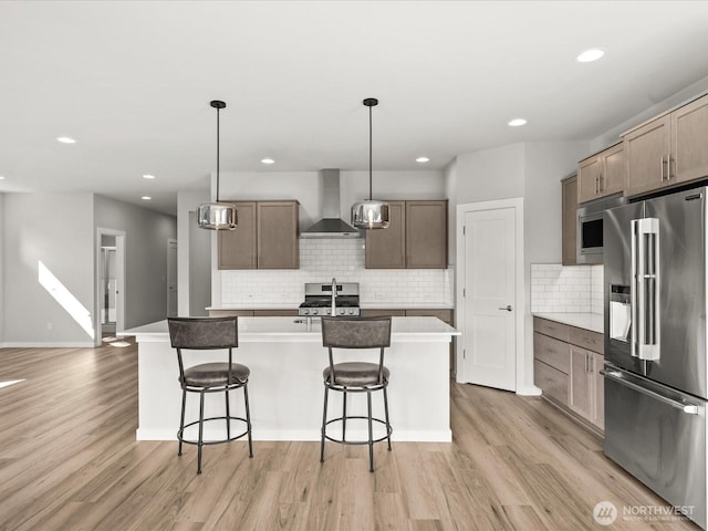 11521 SE 236th St, Kent, WA 98031 - kitchen featuring stainless steel appliances, wall chimney range hood, light wood finished floors, an island with sink, and recessed lighting