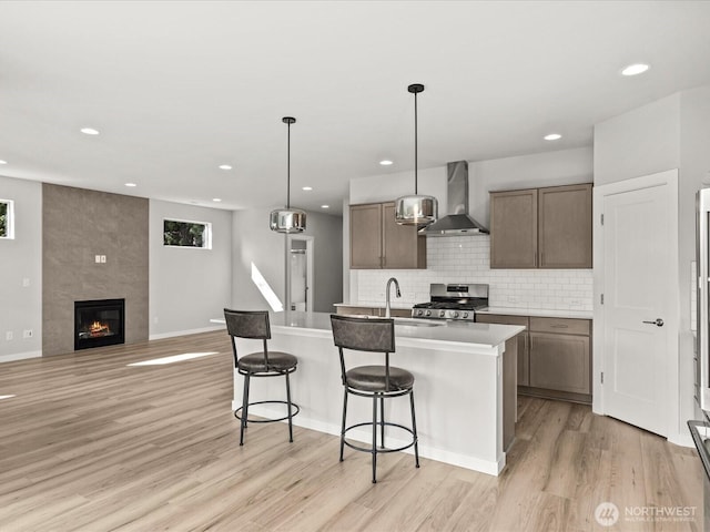 11521 SE 236th St, Kent, WA 98031 - kitchen featuring wall chimney exhaust hood, gas range, a sink, light wood finished floors, and a breakfast bar area