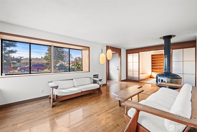 living area featuring baseboards, wood finished floors, and a wood stove