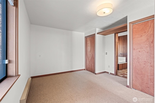 unfurnished bedroom featuring a baseboard radiator, carpet floors, connected bathroom, and baseboards