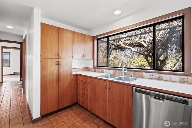 kitchen with light countertops, a sink, stainless steel dishwasher, dark tile patterned flooring, and recessed lighting