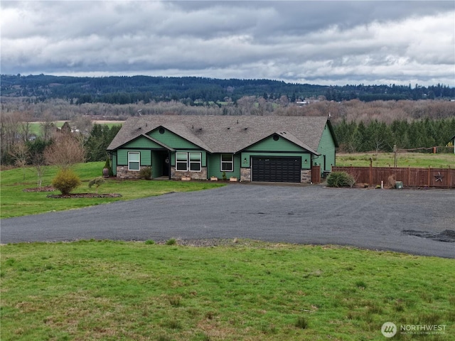 view of front of house featuring a front lawn, driveway, an attached garage, and stone siding