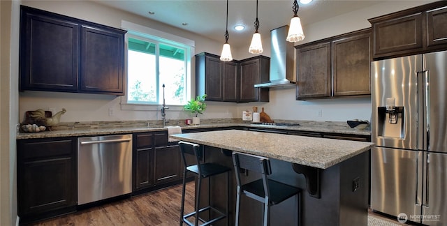 kitchen featuring dark brown cabinetry, wall chimney exhaust hood, dark wood-type flooring, and appliances with stainless steel finishes