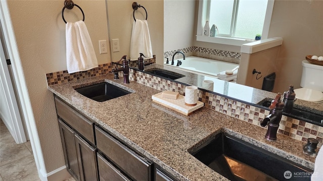 bathroom featuring double vanity, a sink, tasteful backsplash, and toilet