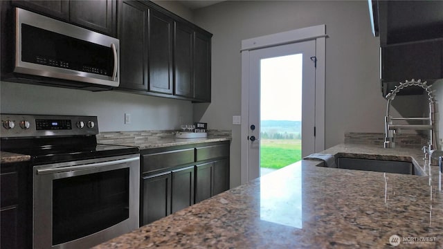 kitchen featuring a sink, light stone counters, and appliances with stainless steel finishes