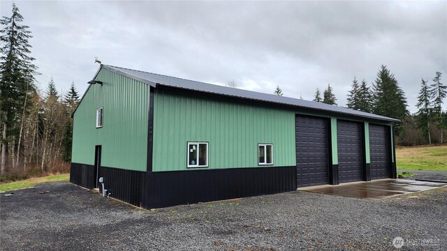 view of side of home featuring metal roof, an outbuilding, and a detached garage